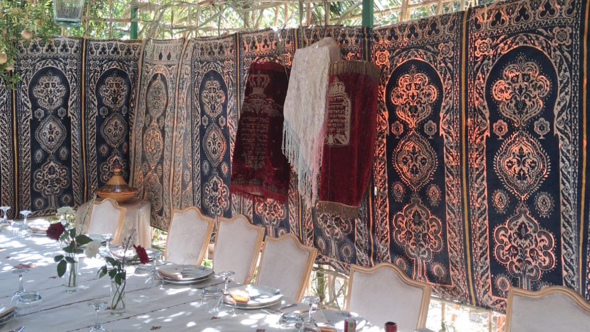 Fête de Souccot à la Résidence montrant un grand châle de prière Tallit blanc suspendu sur du velours bordeaux au-dessus de la table.