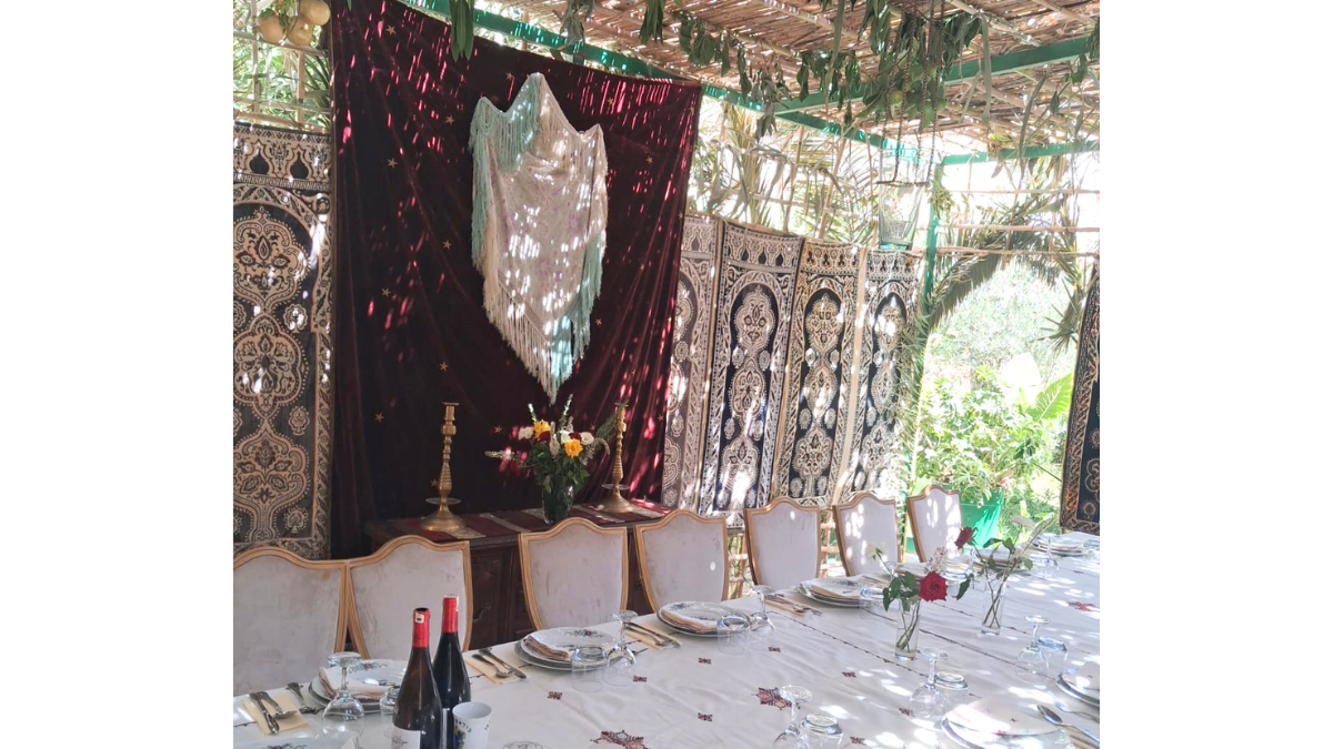 Fête de Souccot à la Résidence mettant en valeur les manteaux de la Torah en velours brodé d'or et le châle de prière Tallit au-dessus de la table.